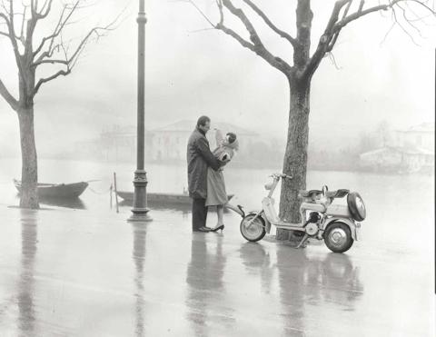 1952 man and woman holding each other next to Lambretta scooter on waterside