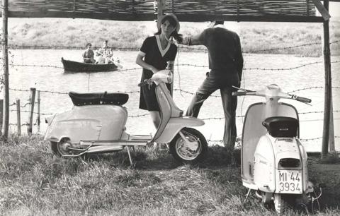 1968 six men on Lambretta scooters next to sign